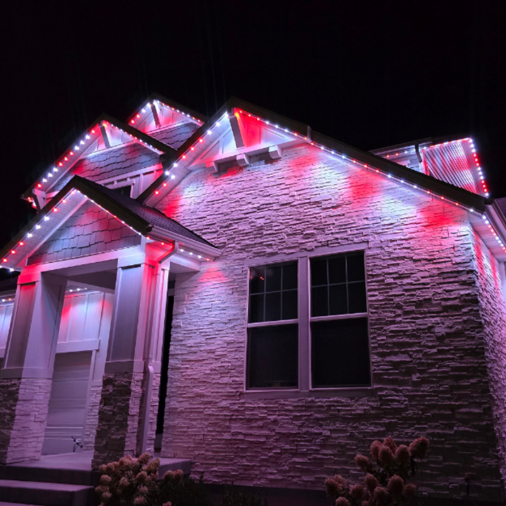 Red and white permanent holiday lighting on stone home